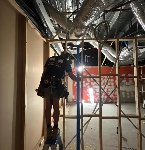 Professional commercial maintenance technician performing interior carpentry repairs in Melbourne office building.